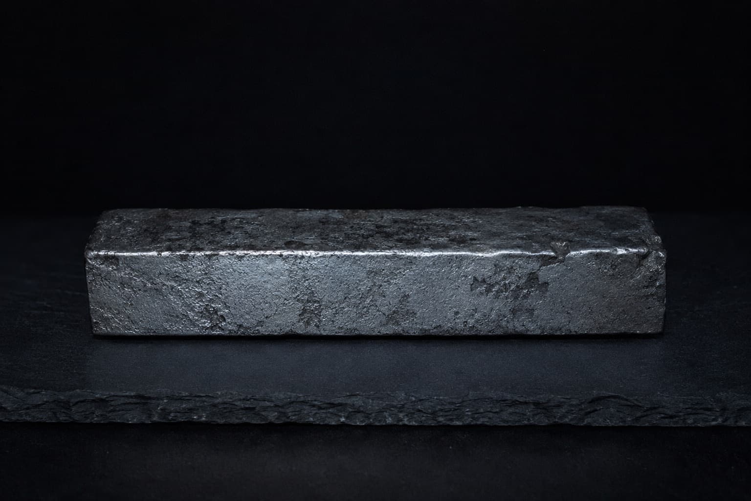 A raw bar of tamahagane steel on dark slate